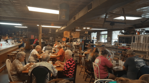 A busy restaurant interior with diners at tables, enjoying meals in a cozy, rustic setting.
