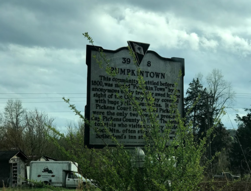 Historical marker for Pumpkintown, detailing its settlement and significance, surrounded by trees and a cloudy sky.