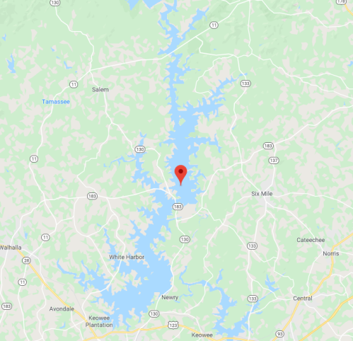 Map showing a blue lake with surrounding green areas and a red marker indicating a specific location.