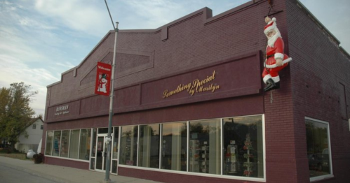 A festive storefront with large windows, featuring a Santa decoration hanging on the side and holiday banners.