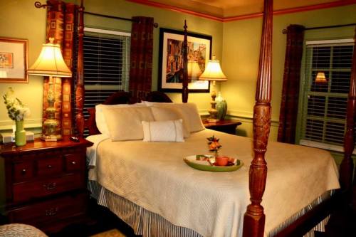Cozy bedroom with a four-poster bed, warm lighting, and decorative accents in green and orange tones.