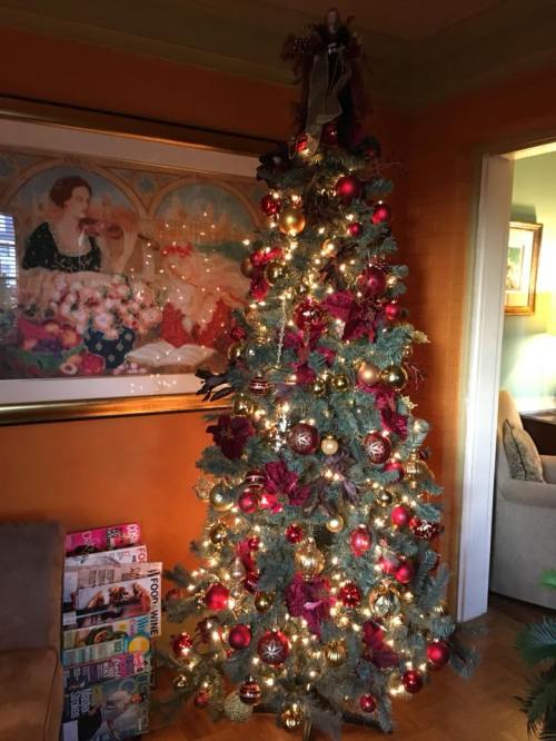 A beautifully decorated Christmas tree with red and gold ornaments, twinkling lights, and a festive angel on top.