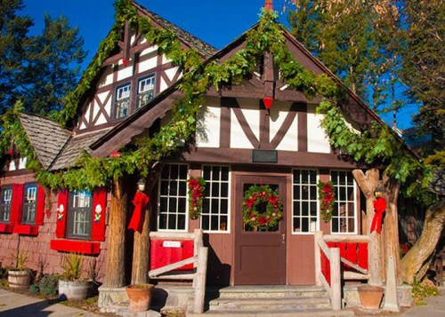 A charming, festive building adorned with greenery and red decorations, set against a clear blue sky.