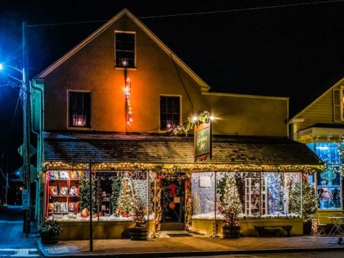 A charming shop decorated with festive lights and holiday decorations at night, creating a warm, inviting atmosphere.