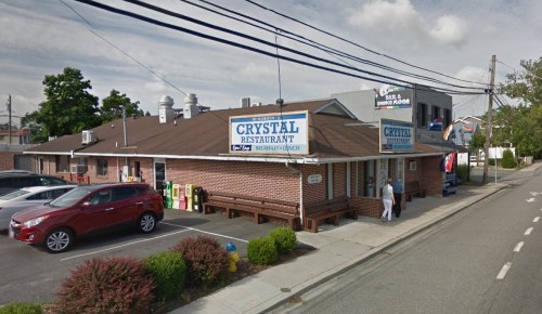 A brick restaurant with a sign reading "Crystal Restaurant," parked cars, and a person entering the building.