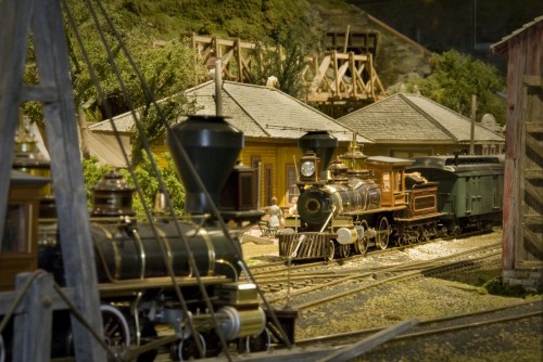 A detailed model train scene featuring vintage locomotives and a miniature town with trees and buildings.