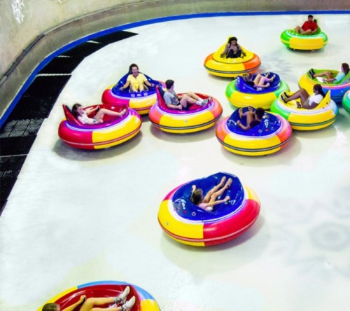 A colorful water park scene with people in inflatable tubes floating in a circular pool.