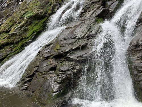 A cascading waterfall flows over moss-covered rocks, creating a serene natural scene.