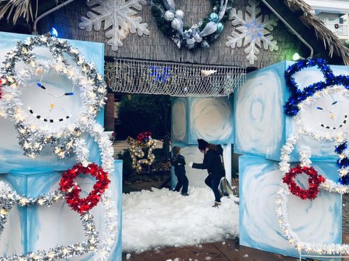 Children play in a snowy scene with festive decorations, including snowman figures and a winter-themed entrance.