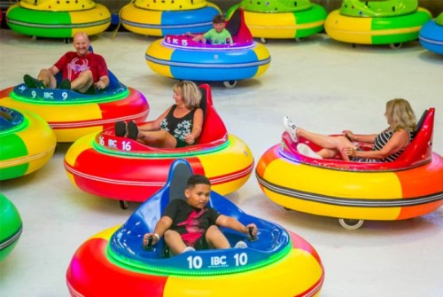 A group of people enjoying bumper cars in a colorful indoor amusement area.