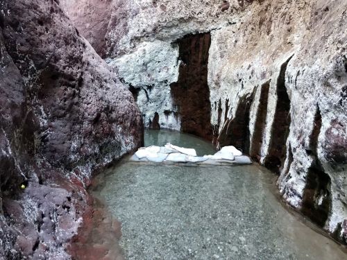 A serene pool of clear water surrounded by rocky, textured canyon walls.