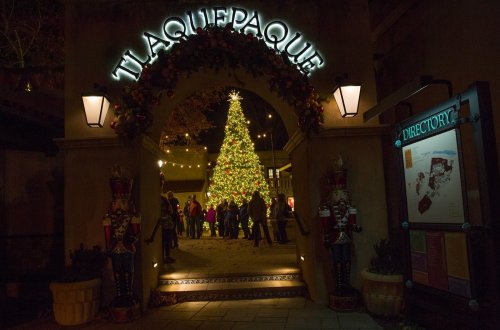 Entrance to Tlaquepaque decorated for Christmas, featuring a large tree and festive lights, with visitors gathered around.