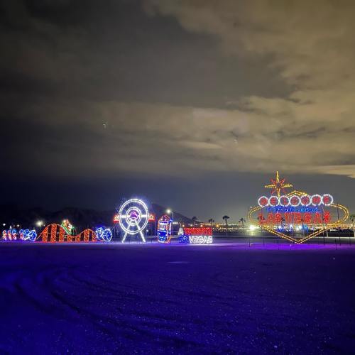 A colorful display of holiday lights featuring various shapes and designs against a night sky.