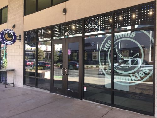 Exterior of Insomnia Cookies store with large glass windows and a round sign, featuring the logo and storefront entrance.