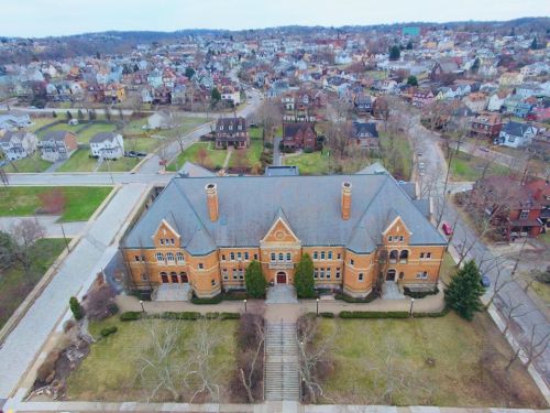 Aerial view of a large brick building surrounded by trees and residential neighborhoods.