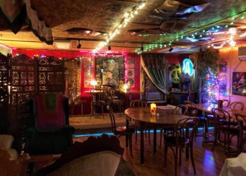 Cozy, colorful café interior with string lights, wooden tables, and eclectic decor, creating a warm atmosphere.