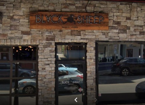 Exterior of a restaurant named "Black Sheep," featuring a stone facade and large windows.