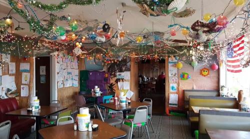 A colorful diner interior with festive decorations, string lights, and children's artwork on the walls.