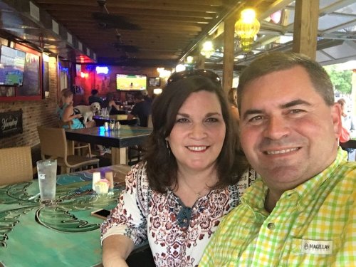 A couple smiles for a selfie at a lively restaurant with colorful decor and people in the background.