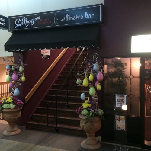 Entrance to DeNunzio's Italian Chophouse and Sinatra Bar, featuring decorative Easter eggs and flowers by the stairs.