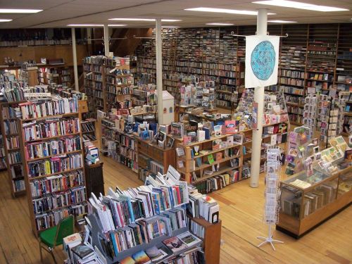 A spacious bookstore filled with shelves of books, cards, and a cozy reading area, all under bright overhead lights.