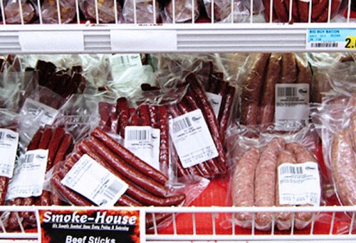 A display of various packaged sausages and beef sticks in a grocery store.
