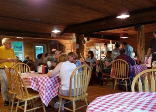 A cozy restaurant interior with wooden decor, checkered tablecloths, and diners enjoying their meals.