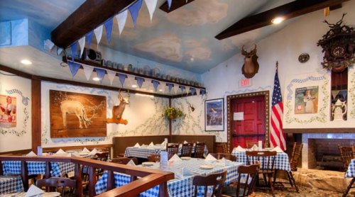 Cozy restaurant interior with checkered tablecloths, rustic decor, and a mounted deer head on the wall.
