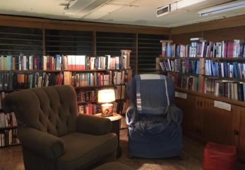 Cozy reading nook with two armchairs, a lamp, and bookshelves filled with books in a warm, inviting room.