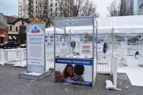 A donation booth for the Dollar Energy Fund at a winter event, with signage and a snowy outdoor setting.