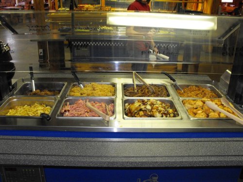 A buffet station with various trays of food, including meats, sides, and toppings, ready for serving.