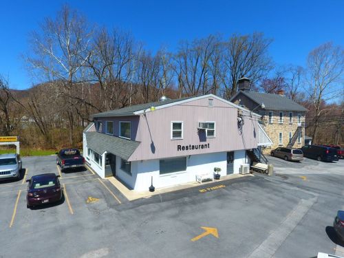 A restaurant building with a parking lot, surrounded by trees and a clear blue sky.