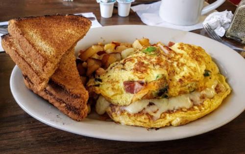 A plate with a fluffy omelette, diced potatoes, and two slices of toasted bread.