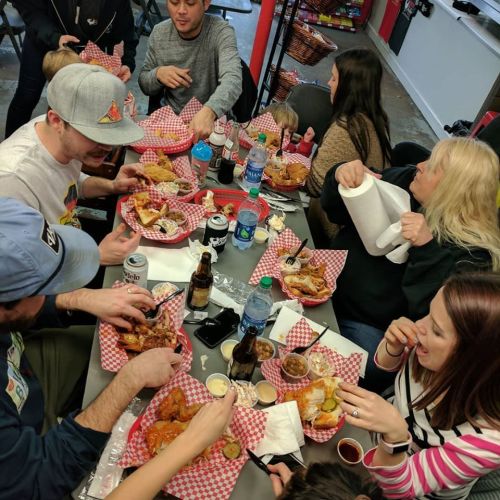 A group of people enjoying a meal together at a table filled with food and drinks, sharing laughter and conversation.