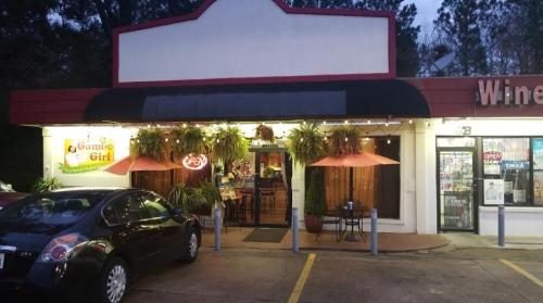 A restaurant with a sign reading "Gumbo Girl," featuring outdoor seating and hanging plants, in a shopping area.