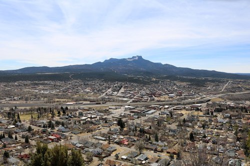 Aerial view of a town with mountains in the background under a clear blue sky.