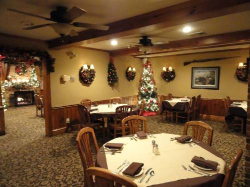 Cozy restaurant interior decorated for Christmas, featuring a tree, festive garlands, and tables set for dining.