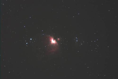 A vibrant nebula surrounded by stars, showcasing bright red and orange hues against a dark background.