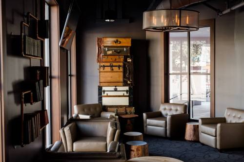 Cozy lounge area with leather chairs, wooden tables, and a stack of vintage suitcases against the wall.