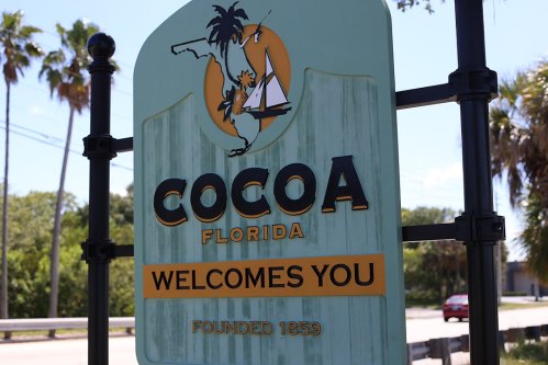 Sign for Cocoa, Florida, featuring a palm tree and sailboat, with "Welcomes You" and "Founded 1859" text.