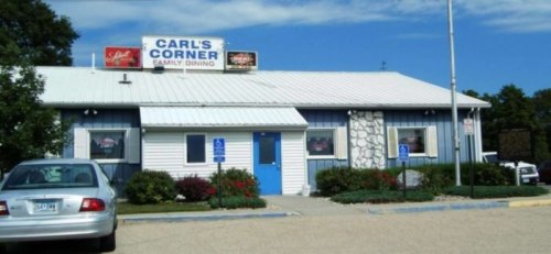 A blue and white family dining restaurant named Carl's Corner, with a parking lot and clear blue sky.