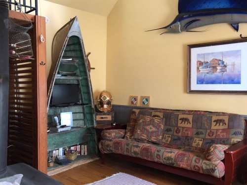 Cozy living room with a boat-shaped shelf, a colorful couch, and nautical decor on the walls.
