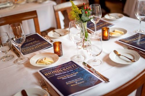 A beautifully set dining table with menus, glasses, and a small flower arrangement.