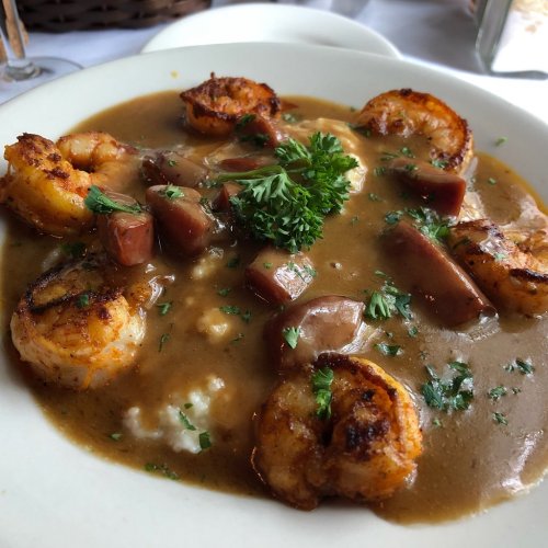 A plate of shrimp and sausage gumbo served over rice, garnished with parsley.