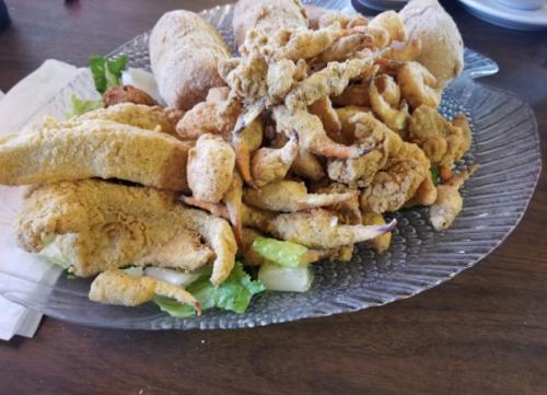 A platter of fried seafood, including crab claws and other fried items, served on a bed of lettuce.