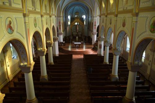 Interior of a church featuring arched ceilings, wooden pews, and religious artwork on the walls.