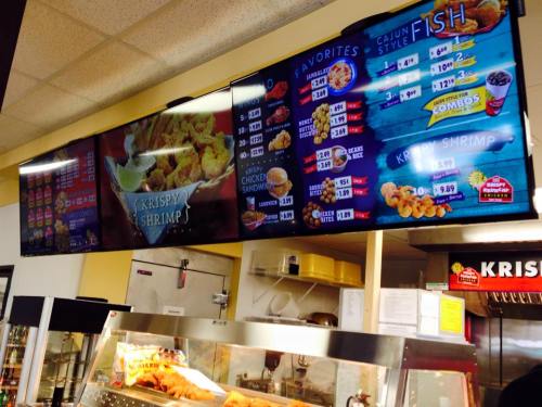 Menu boards displaying food options and prices at a fast-food restaurant, featuring shrimp and fish dishes.