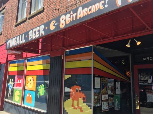 Colorful arcade storefront featuring retro video game characters and a sign for pinball and beer.