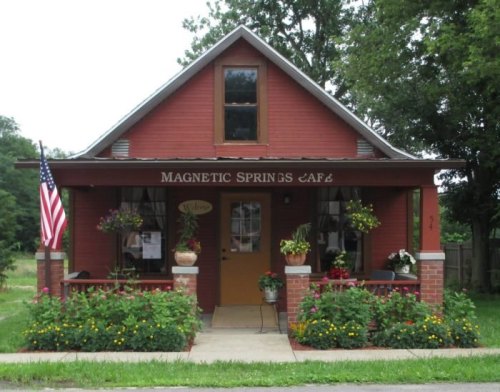 Charming red café with flower boxes, an American flag, and a welcoming entrance surrounded by greenery.