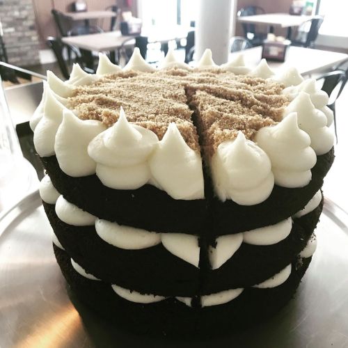 A layered chocolate cake with white frosting and a crumb topping, sliced and displayed on a silver tray.